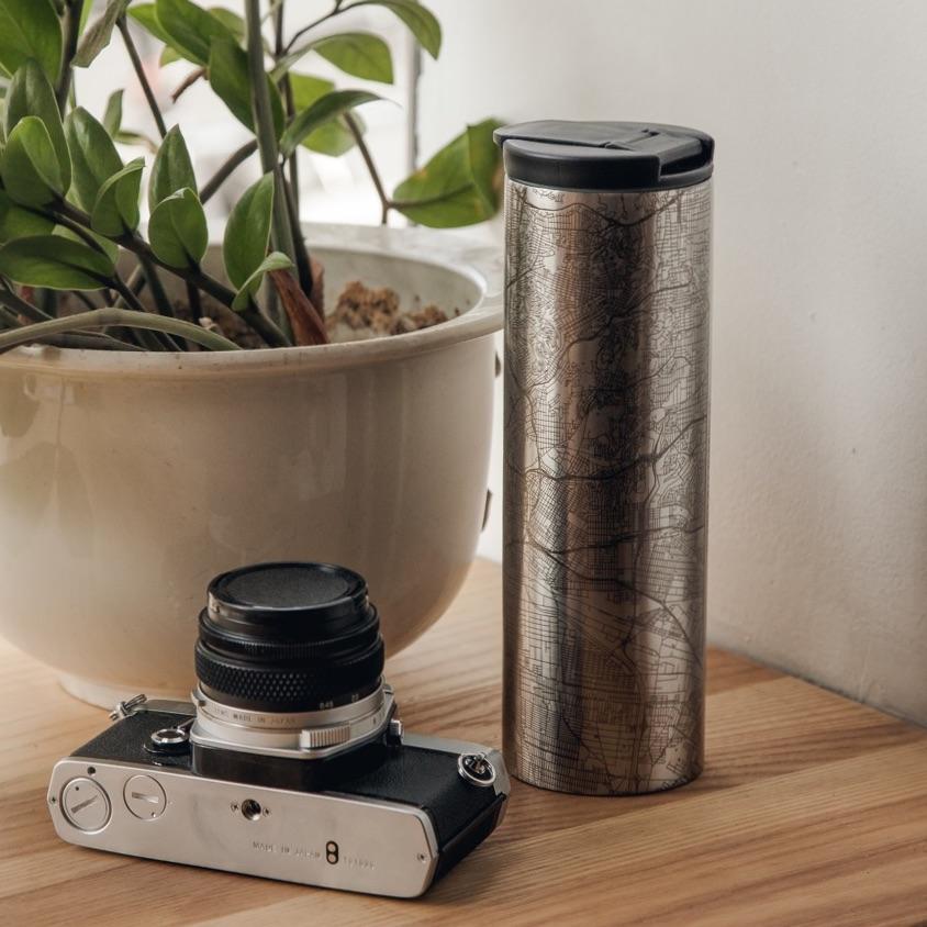 Raleigh - North Carolina Map Tumbler sitting next to a camera and plant on a wooden table